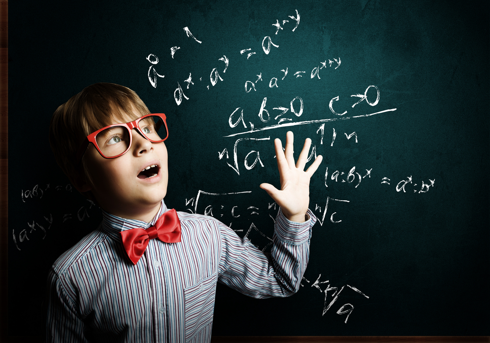 Genius boy in red glasses near blackboard with formulas